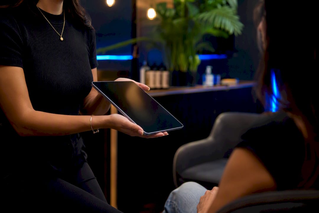 Salon receptionist holding tablet for intake form