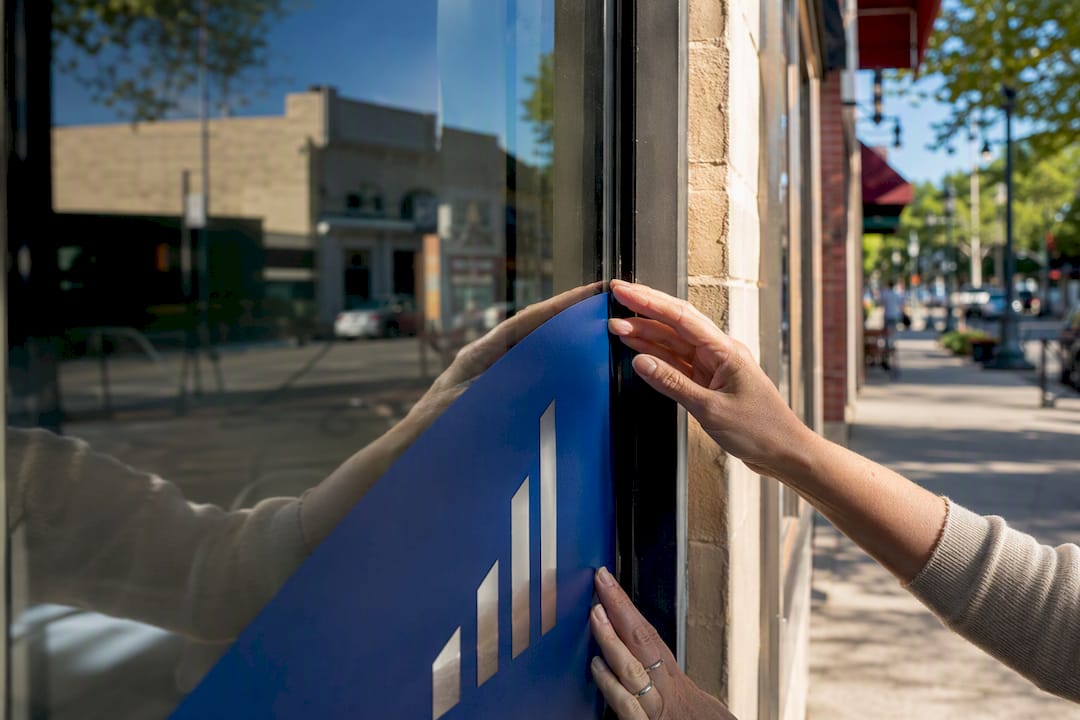 Hands installing signage on storefront window