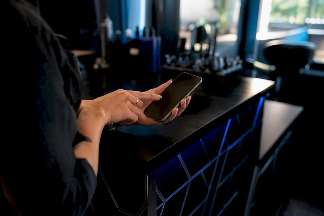 Hand tapping smartphone booking button in salon