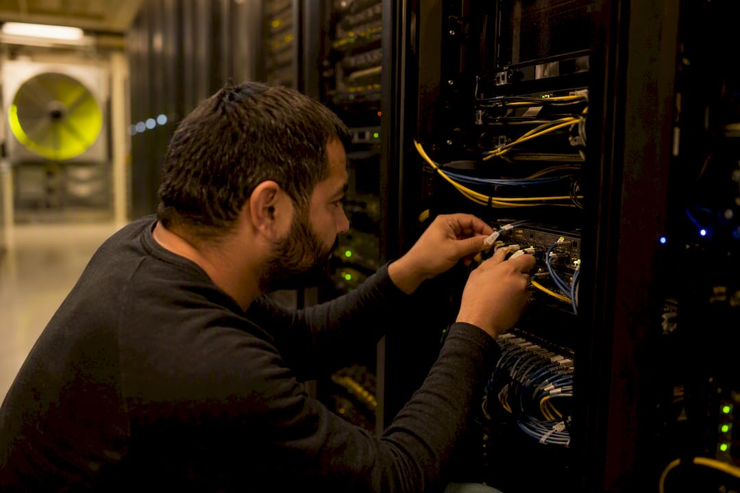 Technician connecting cables in server room