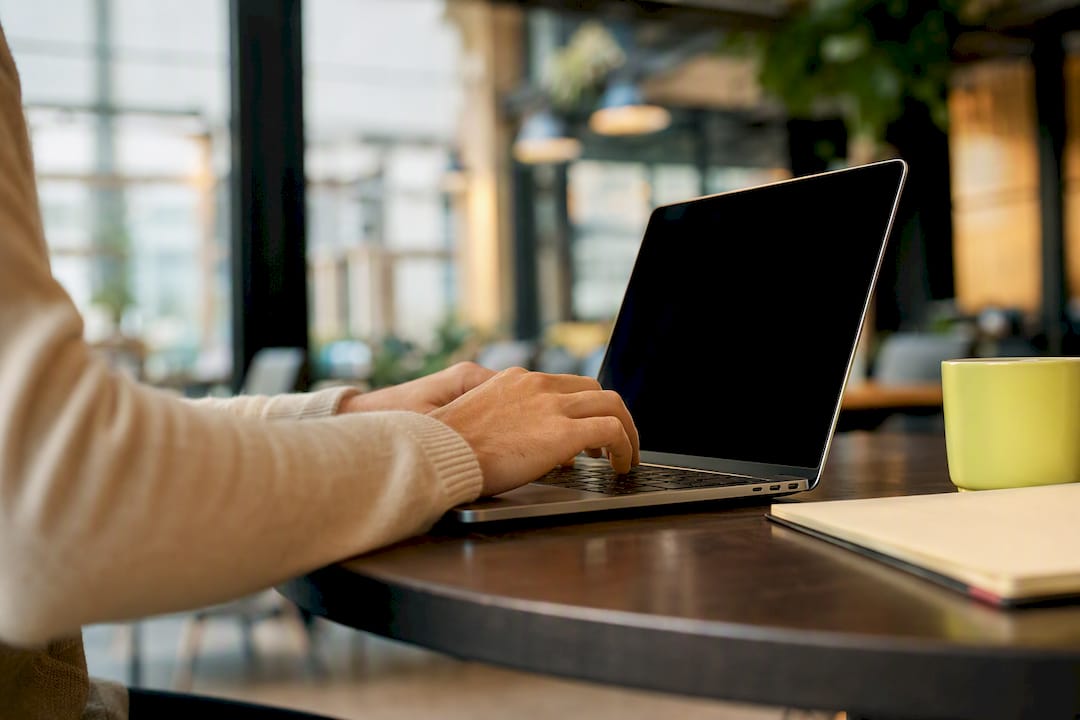 Hands configuring multi-currency payout details on laptop keyboard