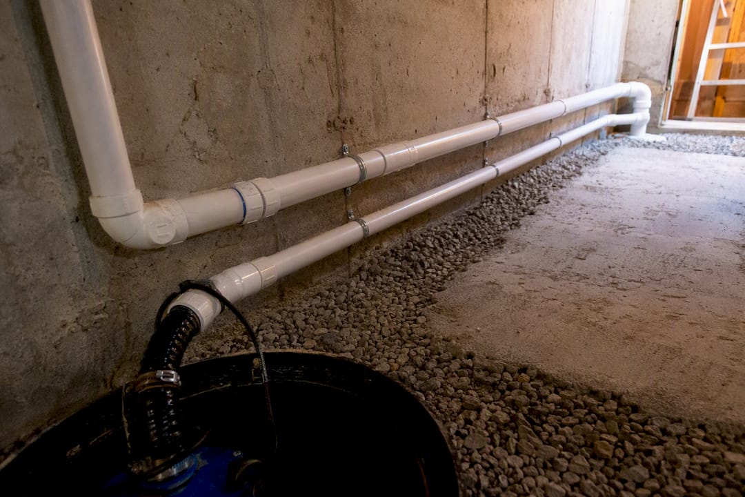 Sump pump discharge plumbing routed above ground