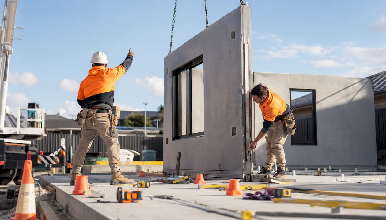 Workers assembling modular concrete panels outdoors