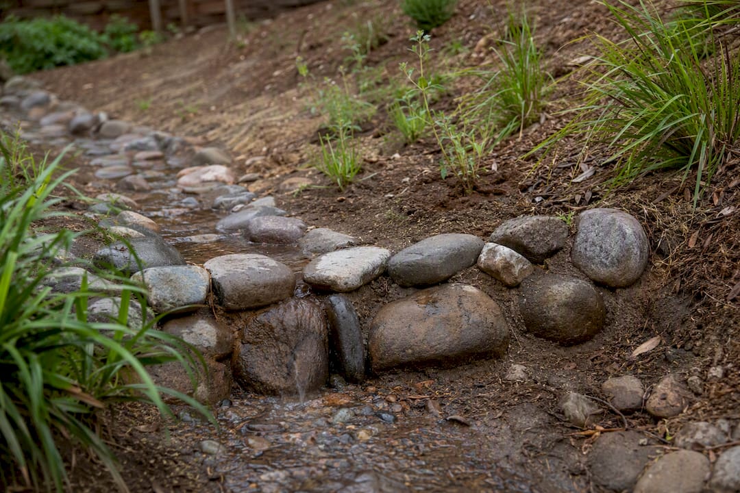 Rock weir slowing runoff on backyard slope