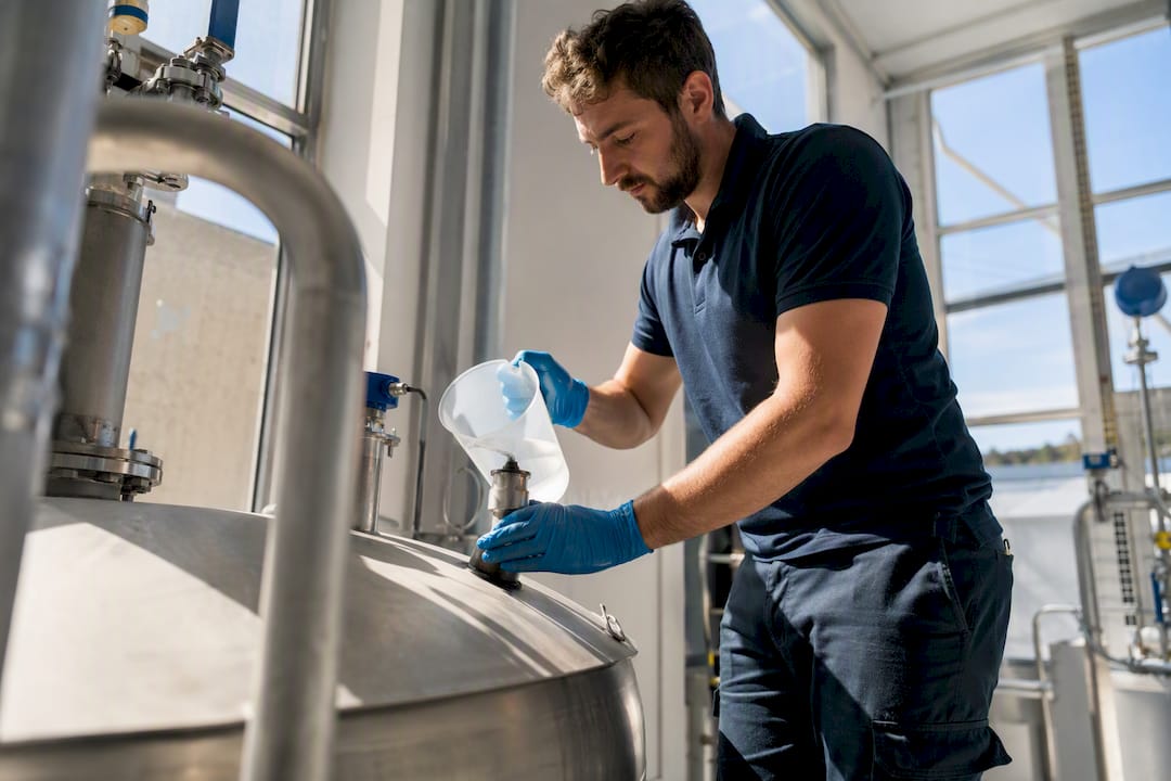 Technician applying chlorination chemical to water tank
