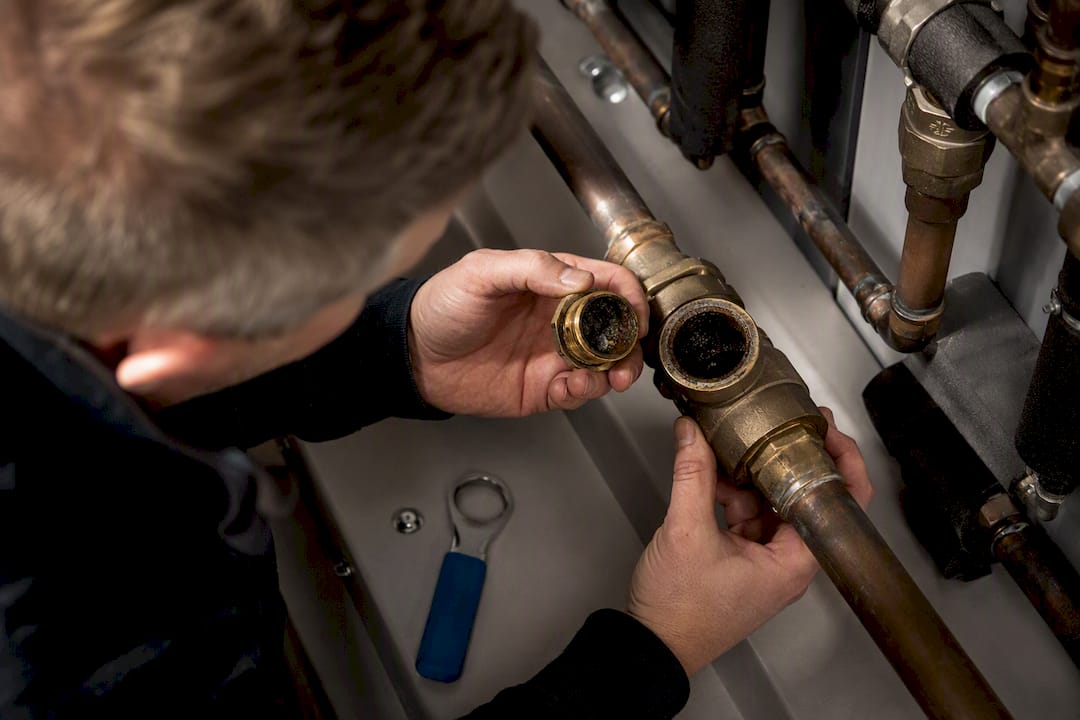 Technician examining scaled shower pipework