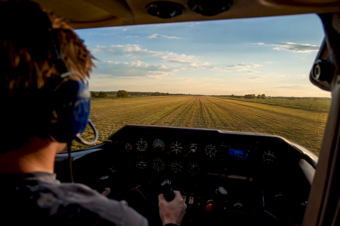 Student pilot flaring above a grass runway