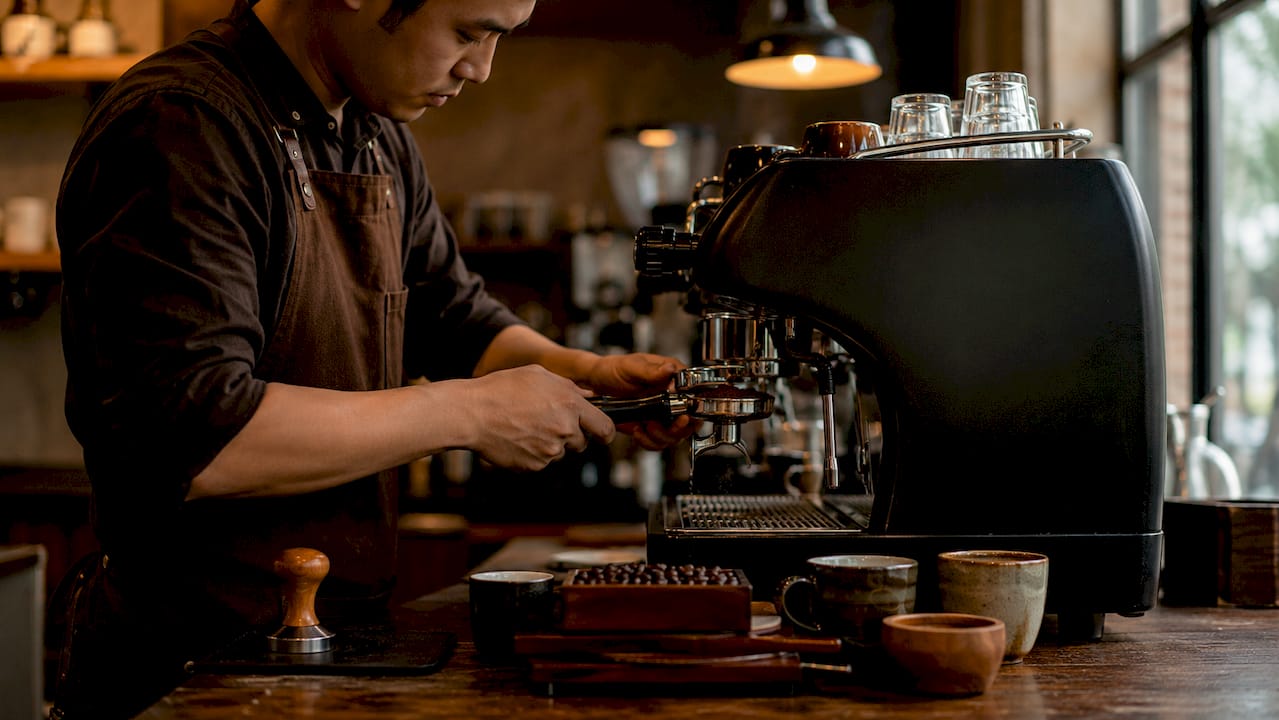 Barista blooming coffee grounds during espresso brewing