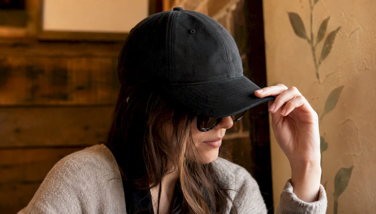 Hand adjusting baseball cap brim with sunglasses