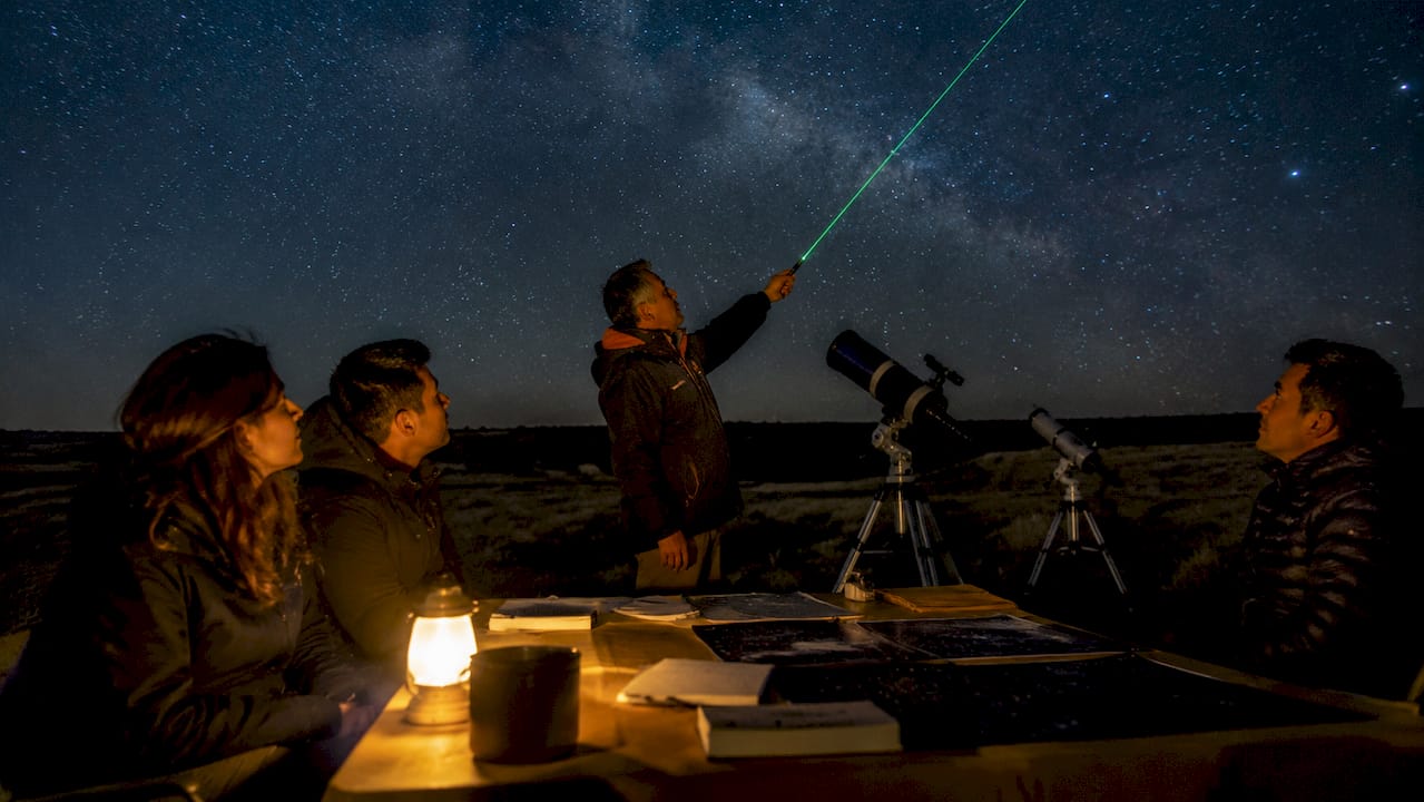 Monitor impartiendo una charla de astronomía a un grupo al aire libre