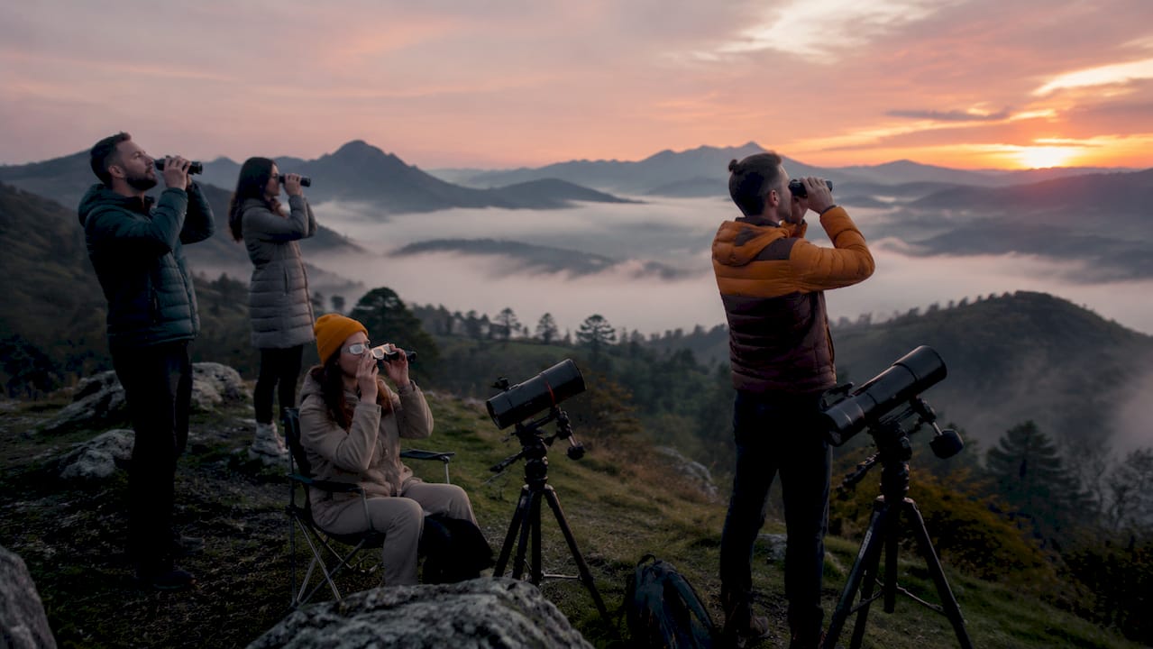 Un grupo de personas se reúne en un mirador junto al mar para contemplar el eclipse.