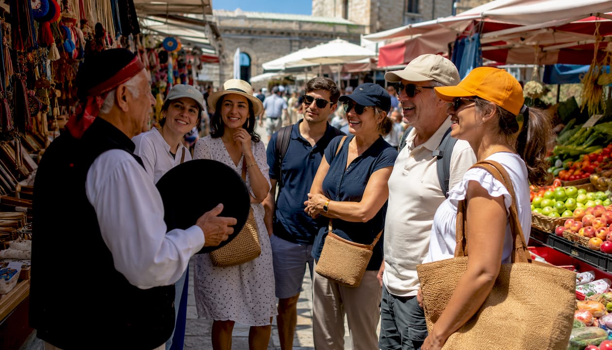 Un grupo de turistas atiende a las explicaciones de su guía en la plaza.