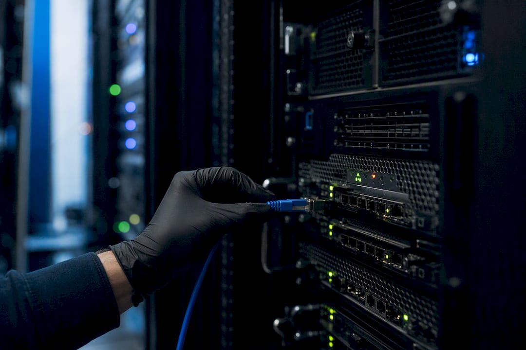 Hand connecting data cable in server rack