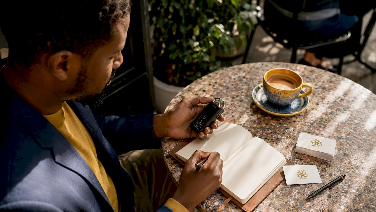 Hands using voice recorder and taking notes