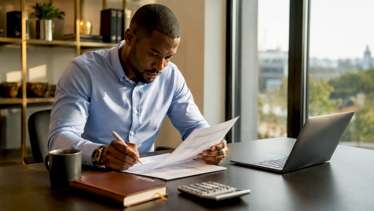 Hands annotating audited financial statements on table