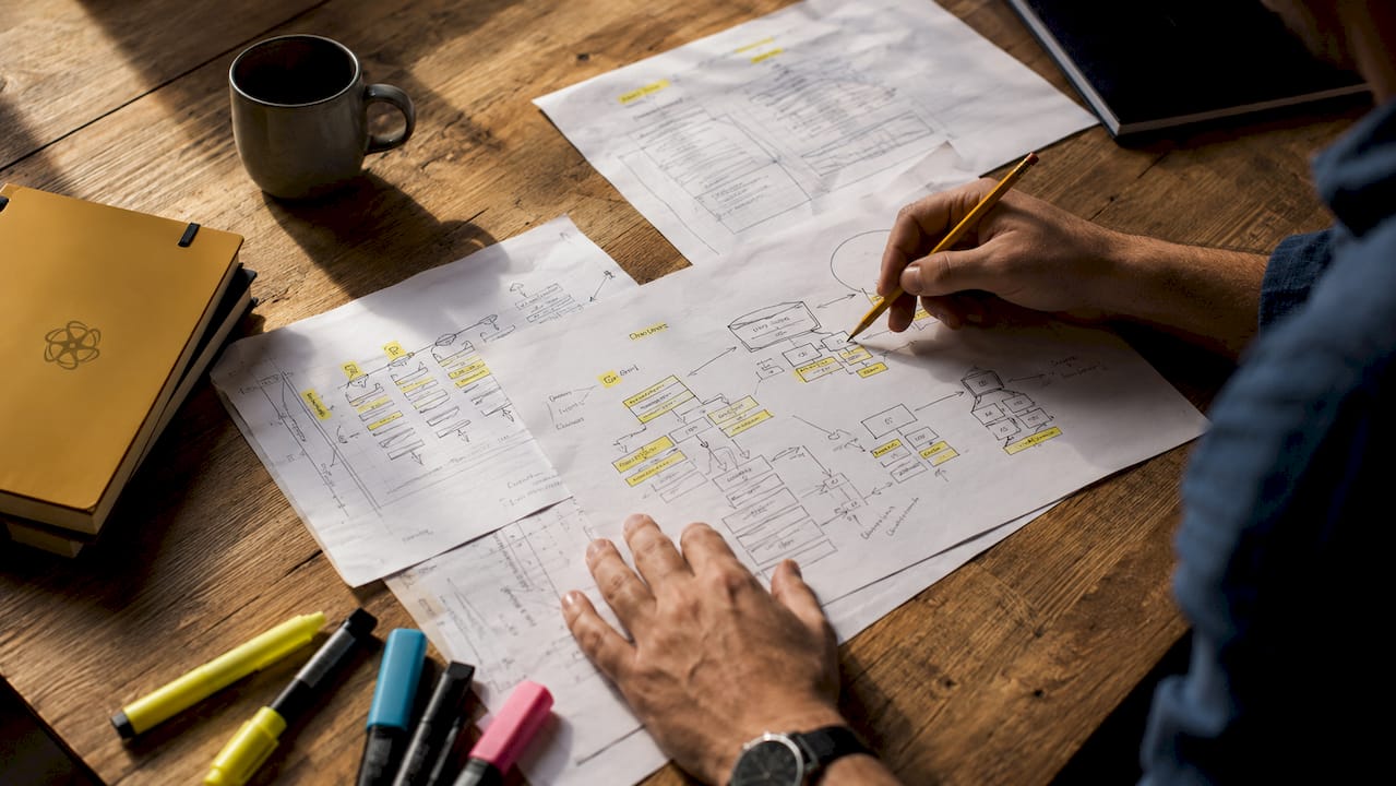 Hands working on business process input-output diagrams