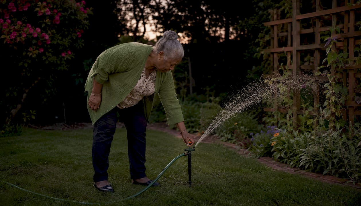Man adjusting sprinkler at sunset