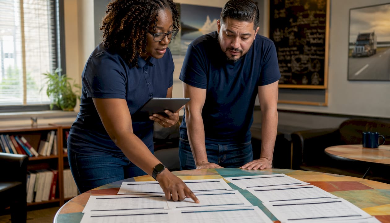 Two dispatchers reviewing linehaul driver schedules in office