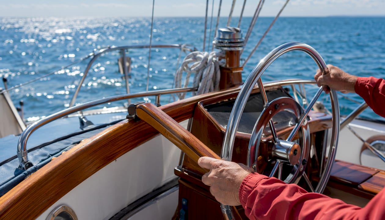 Classic wooden tiller and steering wheel on boat