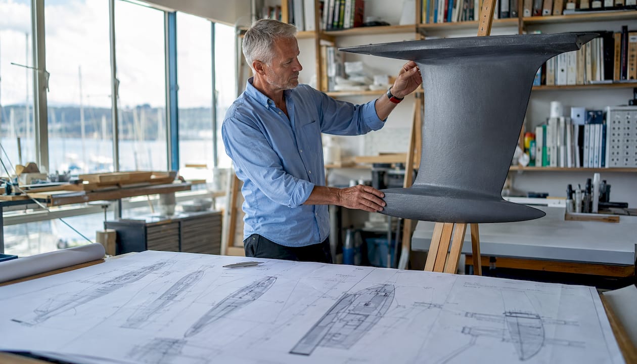 Hands holding fin keel model in marine engineer office
