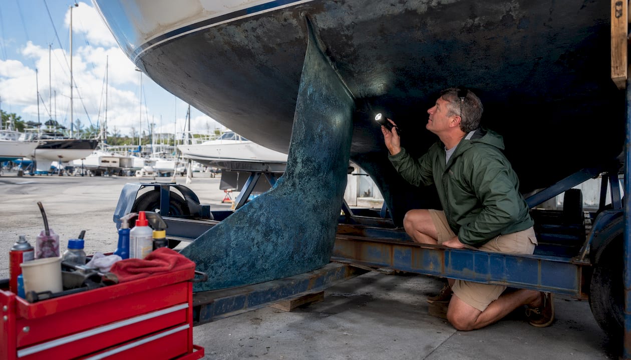 Sailor inspecting boat keel ballast outdoors