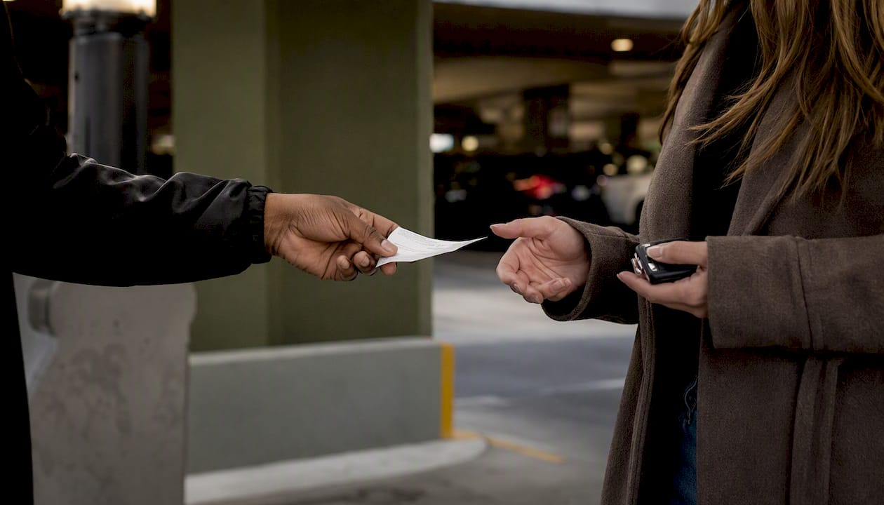 Valet attendant handing parking ticket to guest