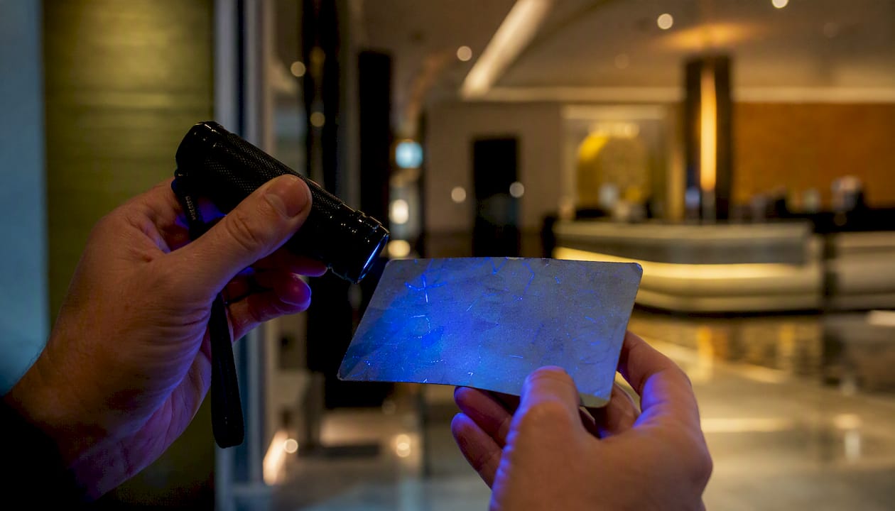 Hands verifying casino ticket under UV lamp