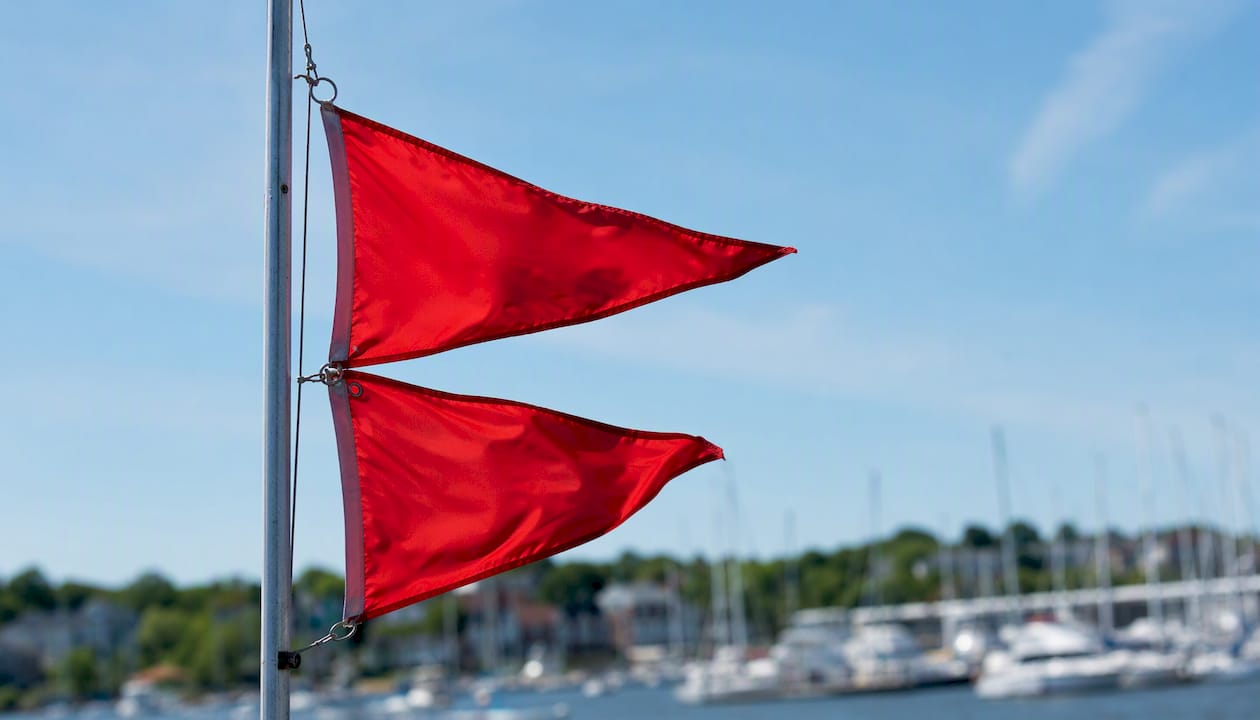 Two red pennants flying on a marina flagpole indicating gale warning