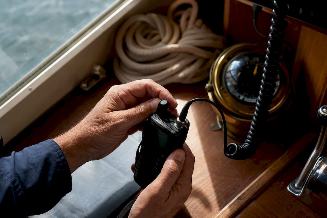 Hands adjusting marine VHF radio on boat helm