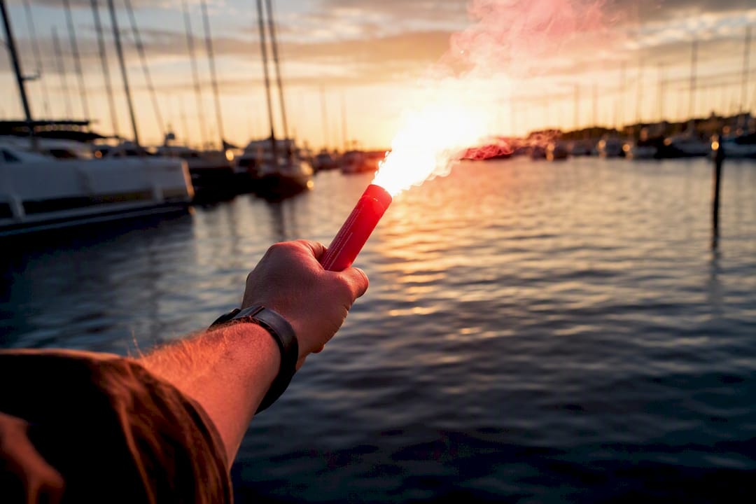 Hand firing marine flare safely over water