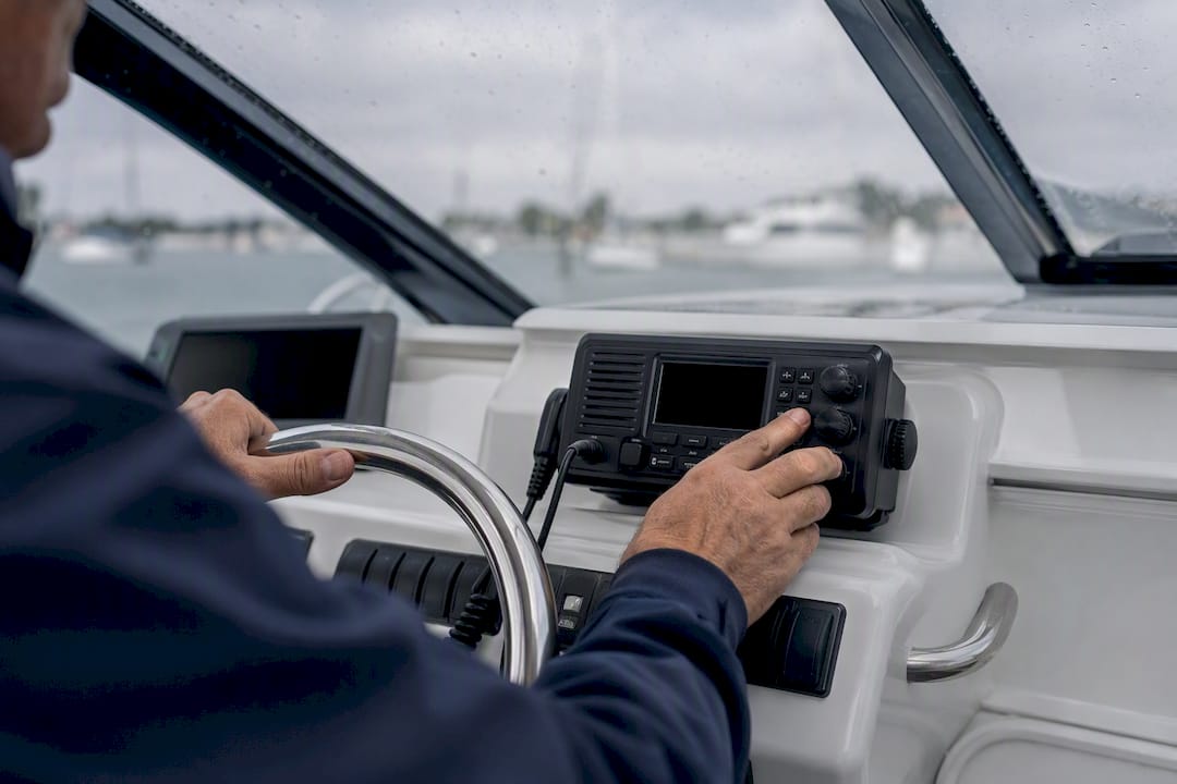 Hands tuning marine VHF radio at boat helm