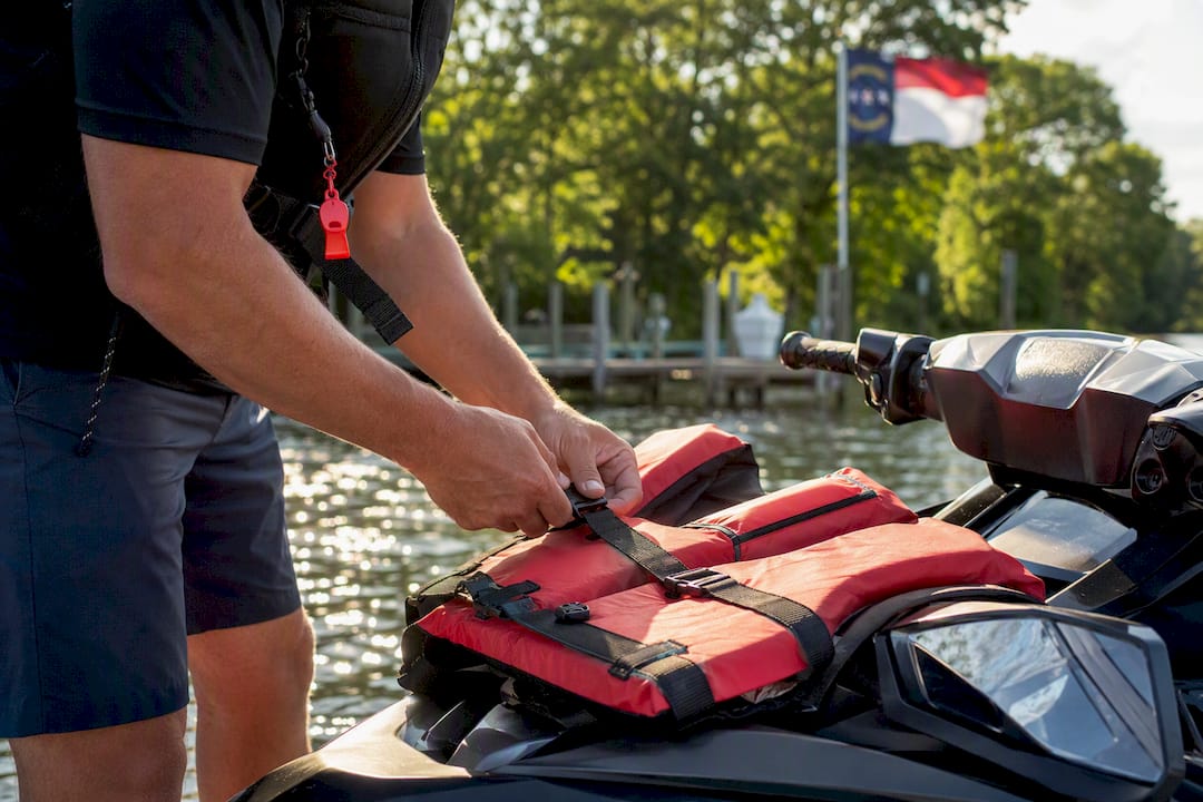 Operator adjusting life jacket on jet ski