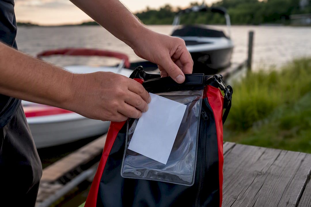 Hands placing temporary boating certificate in waterproof holder