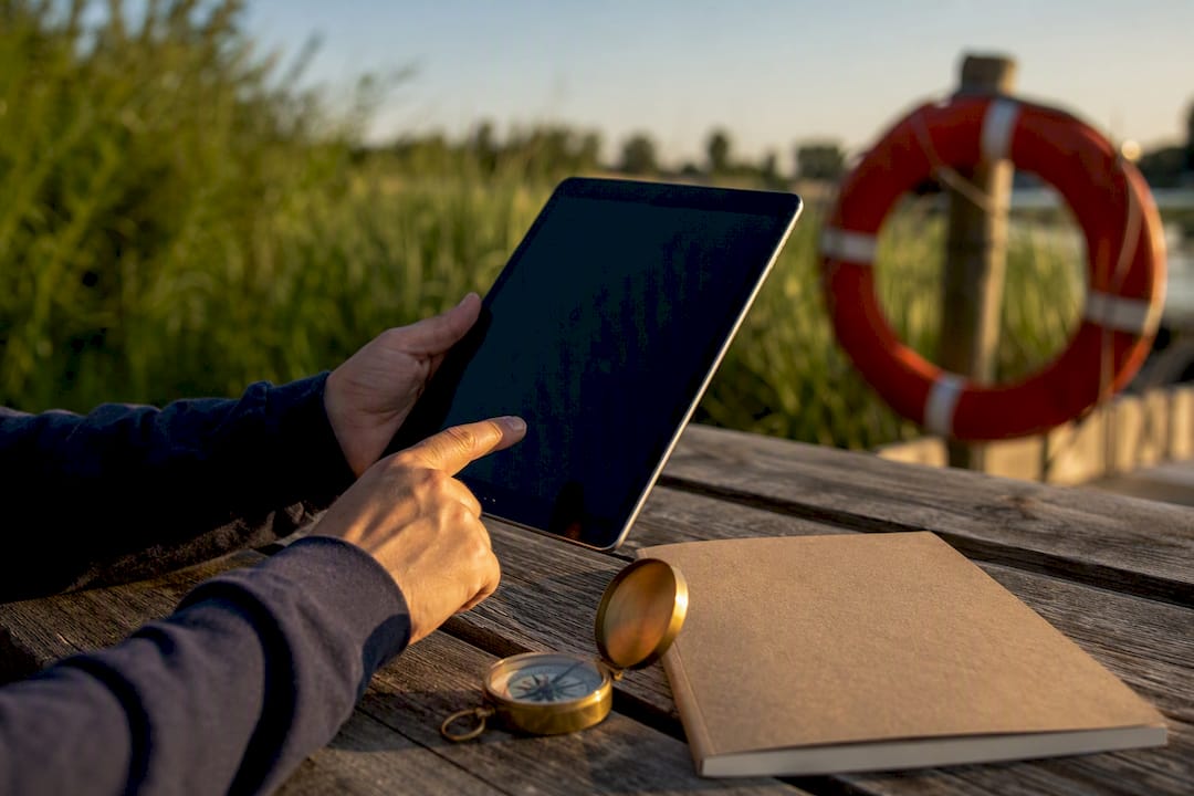 Hands pointing to tablet amid boating study materials