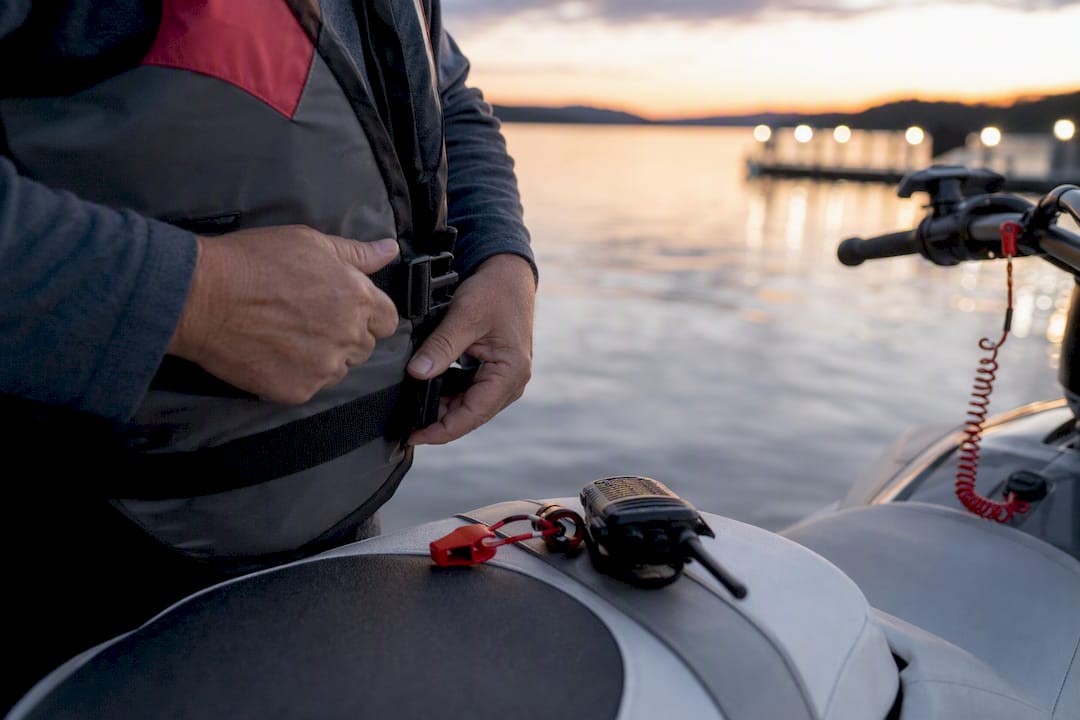 Hands fastening PFD on watercraft operator