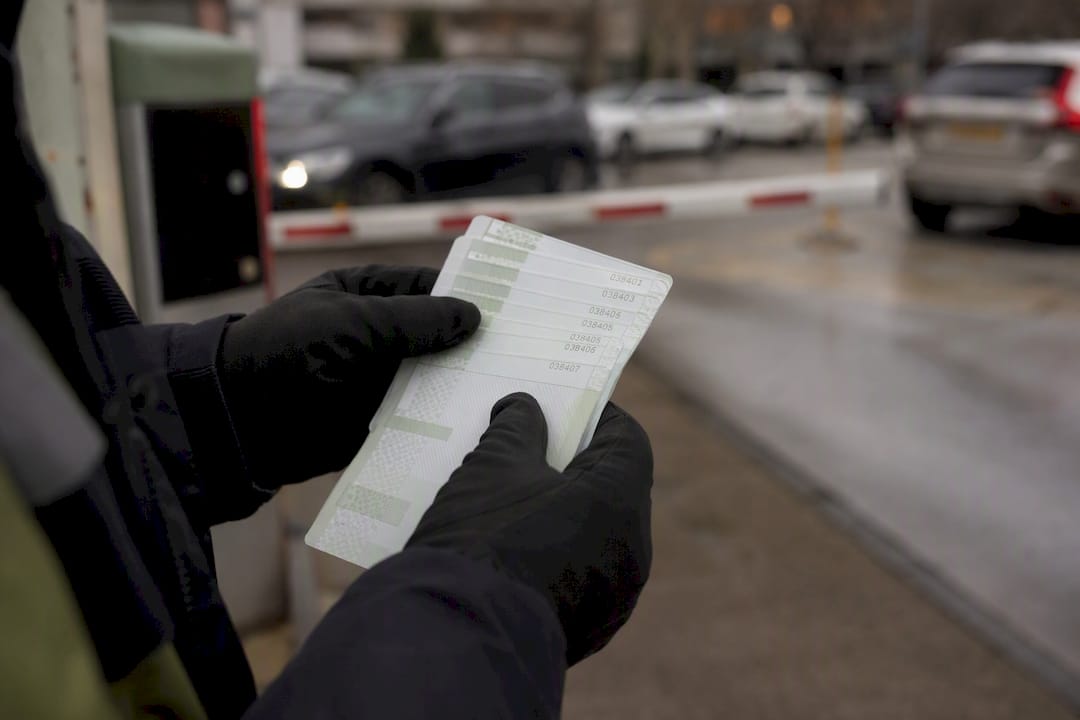 Hands holding sequentially numbered parking tickets