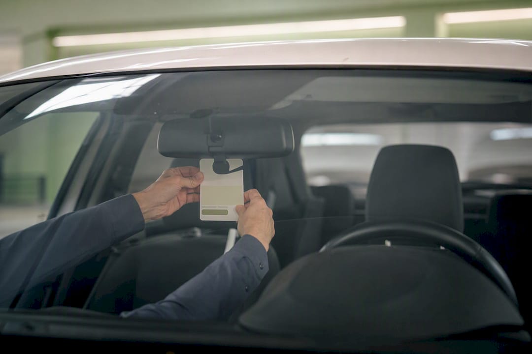 Hands placing parking hang tag on mirror