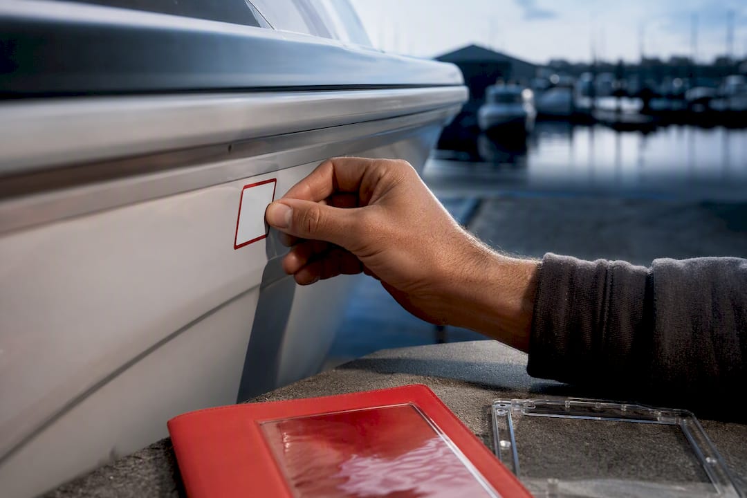 Boater applying registration decal to hull