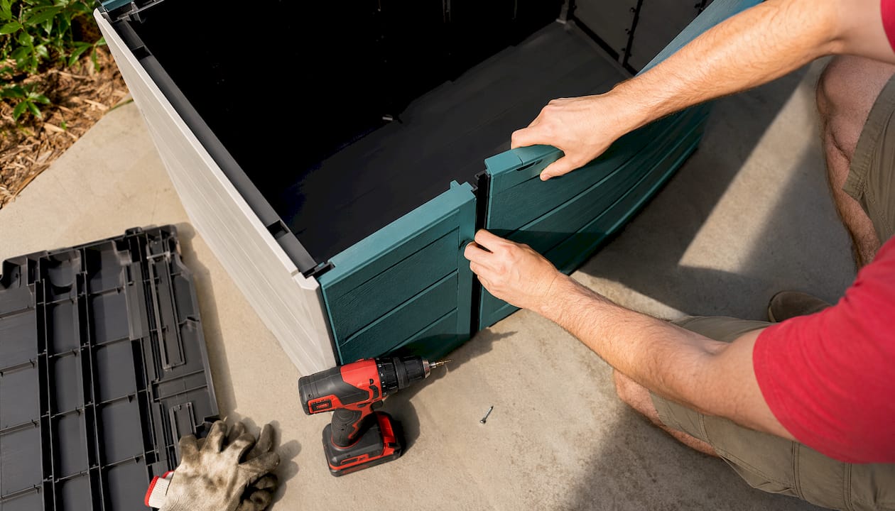 Hands assembling Keter resin storage box outdoors