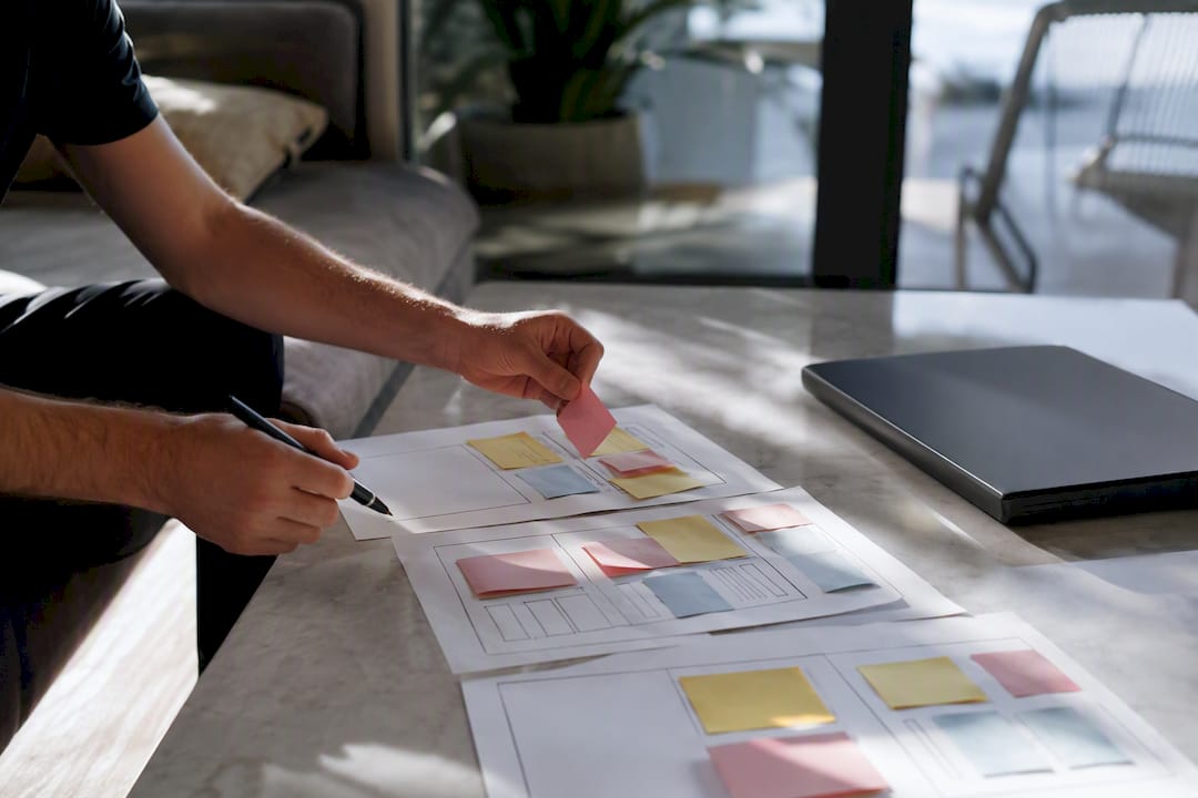 Hands arranging notes for landing page design