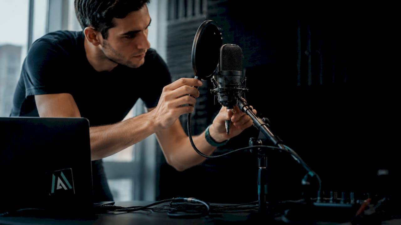 Hands adjusting cardioid microphone with pop filter