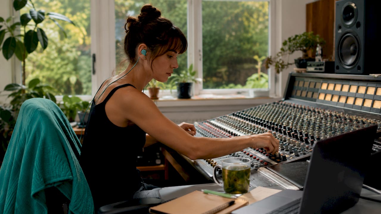 Female engineer adjusting mixing console knobs