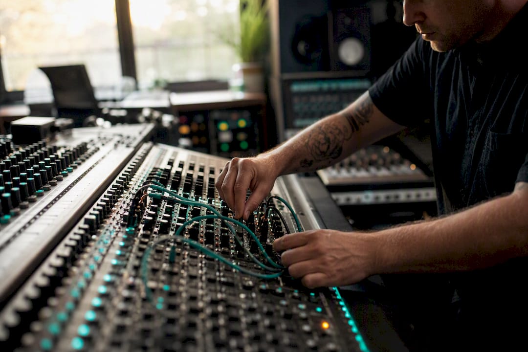 Hands connecting cables on mixing console bus section