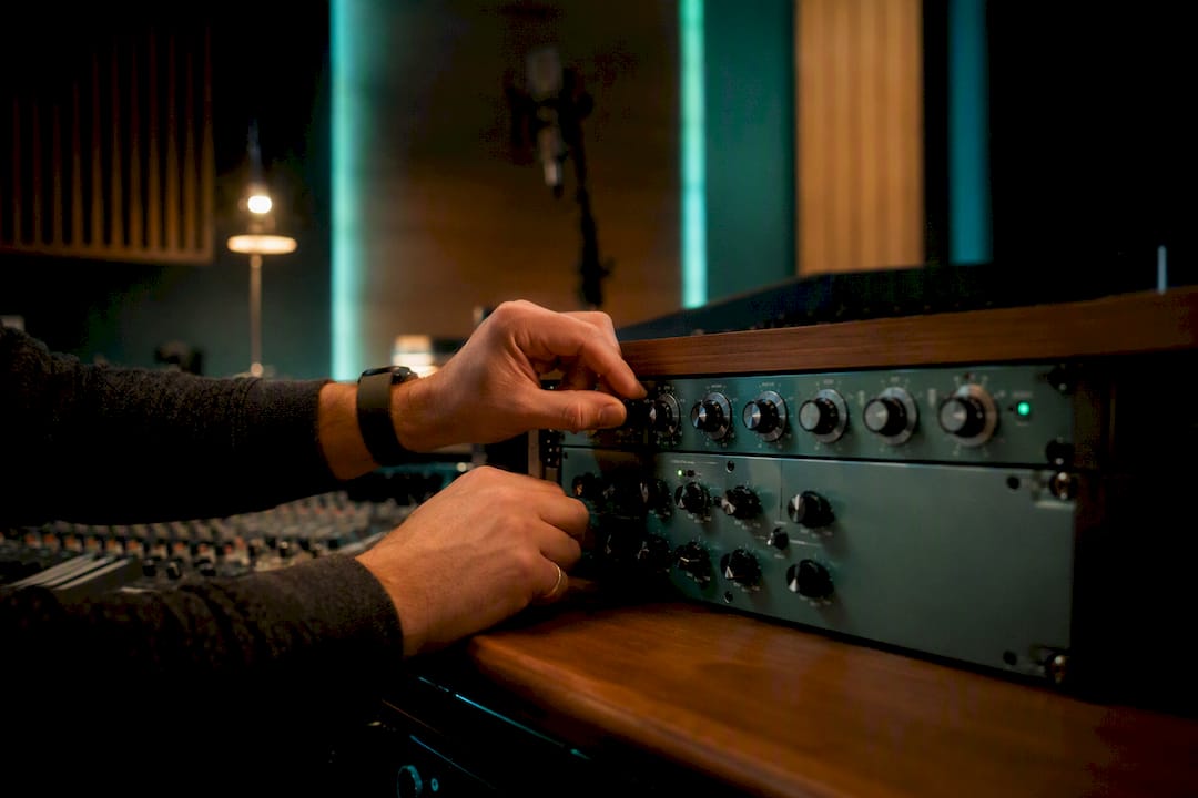 Hands adjusting analog effects in mixing studio