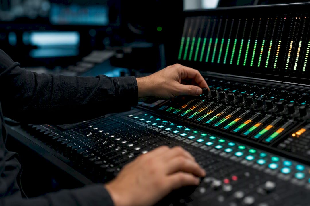 Hands checking audio levels on mixing desk meters