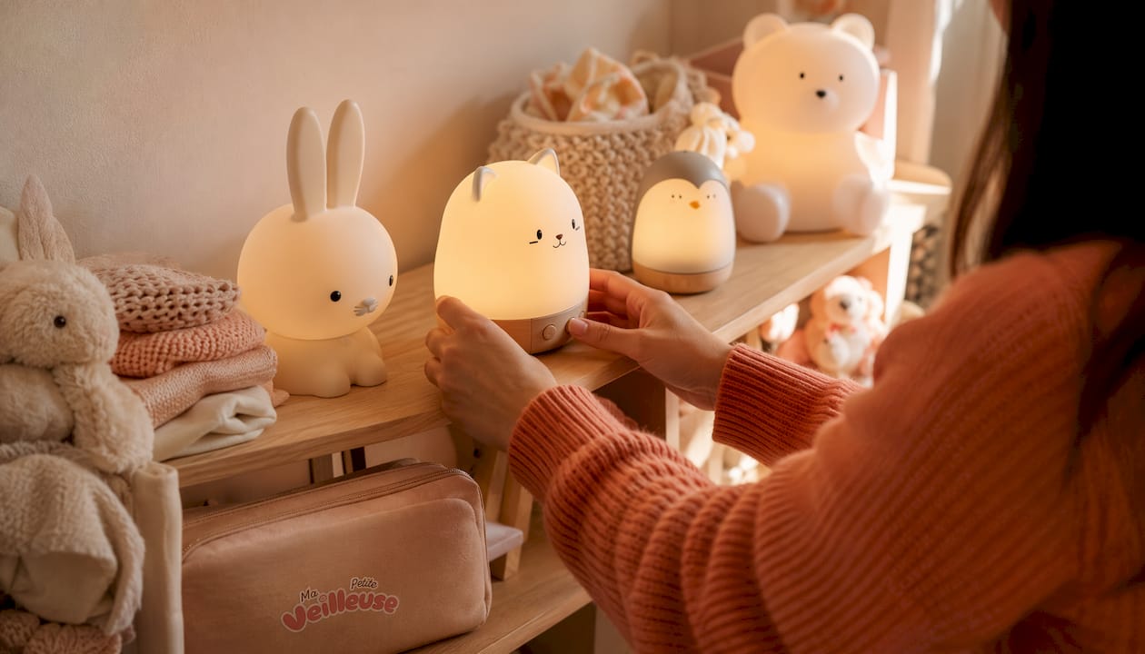 Des petites mains choisissent une veilleuse et un doudou pour bébé.