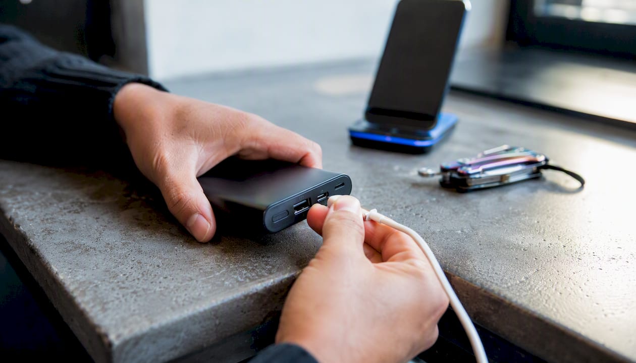 Hands plugging cable into power bank