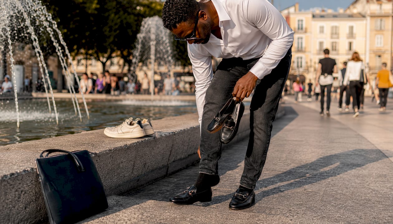 Man swapping trainers for loafers outdoors
