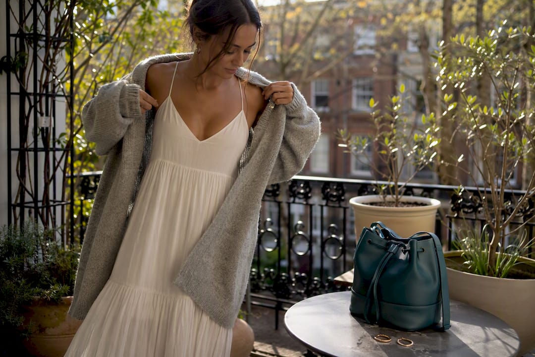 Woman layering neutral slip dress with cardigan