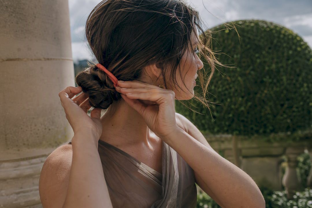 Hands securing a low chignon outdoors